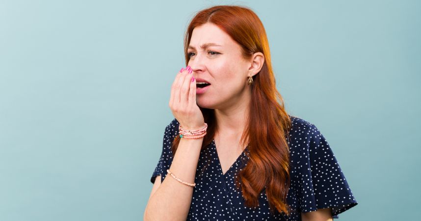women blowing air from her mouth to smell her own breath