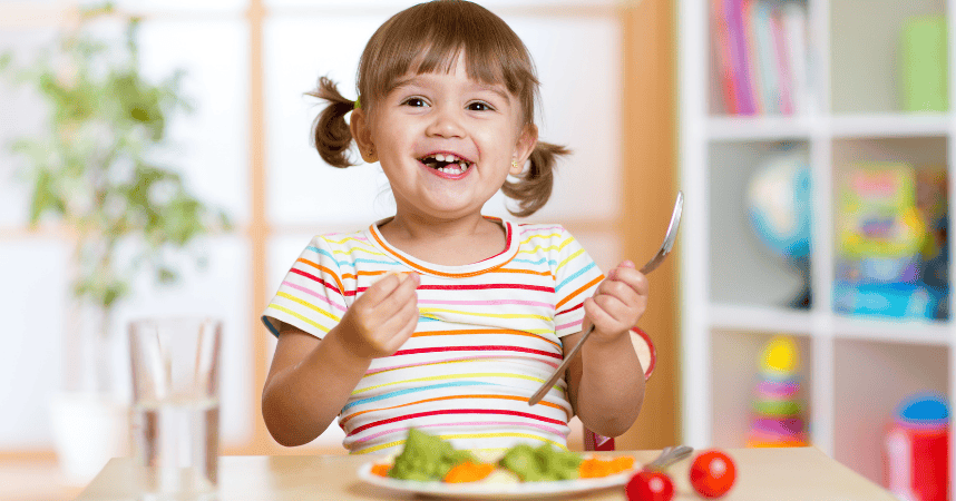 Child happily eating a balanced diet meal with fruits and vegetables, promoting good oral health and nutrition.