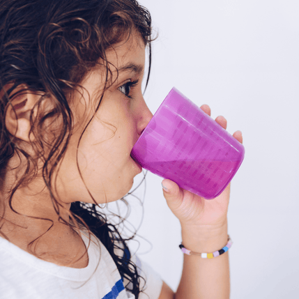 Child rinsing mouth with a pink cup, demonstrating proper oral hygiene practices during pediatric dental care.