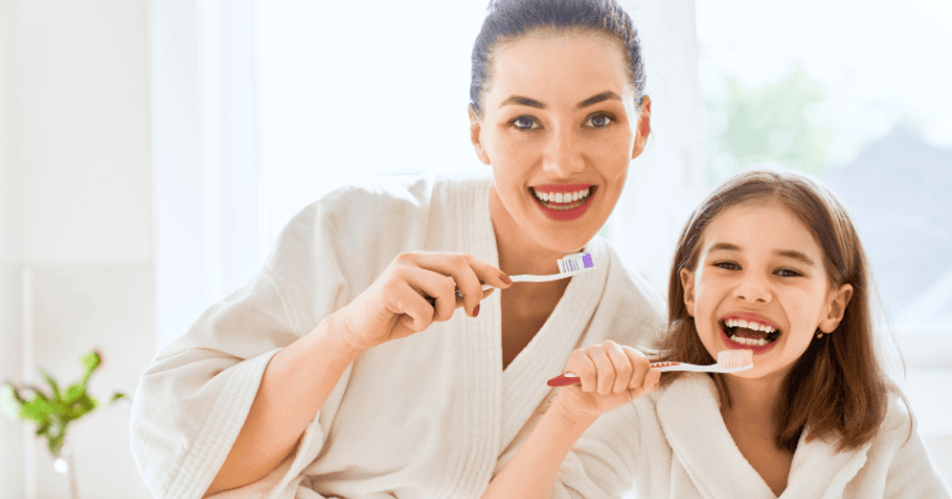 A Mother and her daughter brushing teeth together