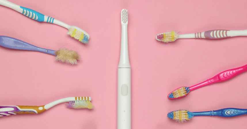 Comparison graphic of electric versus manual toothbrushes, featuring colorful toothbrush illustrations on a pink background, highlighting effectiveness in dental hygiene.