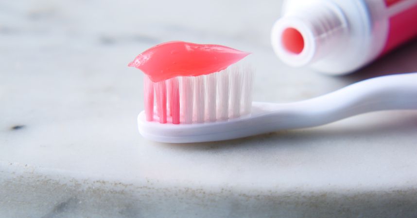 pink and white toothbrush with red toothpaste on it
