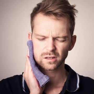 Wisdom tooth pain relief concept with a concerned individual holding their jaw, emphasizing dental discomfort and the importance of emergency dentistry services.